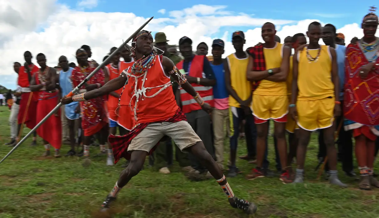 Seorang pria Maasai Moran melemparkan tongkat selama kompetisi Olimpiade Maasai 2018 di Kimana, Kenya (15/12). Olimpiade Maasai  sudah diadakan setiap dua tahun sejak 2012. (AFP Photo/Yasuyoshi Chiba)
