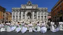 Pengantin perempuan yang mengenakan gaun pernikahan mereka melakukan protes dengan flashmob di Trevi Fountain, Roma, Selasa (7/7/2020). Mereka memprotes kebijakan pemerintah Italia yang masih melarang adanya acara pernikahan, meski penerapan lockdown sudah dilonggarkan. (Tiziana FABI/AFP)