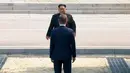 Presiden Korea Selatan, Moon Jae-in menyambut kedatangan Pemimpin Korea Utara, Kim Jong-un di Zona Demiliterisasi (DMZ), Panmunjom, Jumat (27/4). Keduanya berjabat tangan sambil menempatkan senyum di bibir masing-masing. (Korea Broadcasting System via AP)