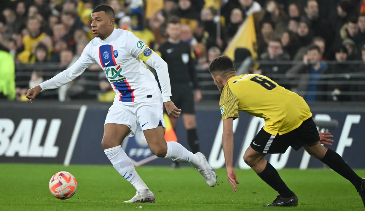 <p>Penyerang PSG, Kylian Mbappe membawa bola dari kawalan pemain Pays de Cassel, Clement Boudjema pada pertandingan babak 32 besar Piala Prancis di stadion Bollaert-Delelis di Lens, Prancis pada 23 Januari 2023. Kemenangan telak itu mengantar Les Parisiens ke babak 16 besar Coupe de France. (AFP/Francois Lo Presti)</p>