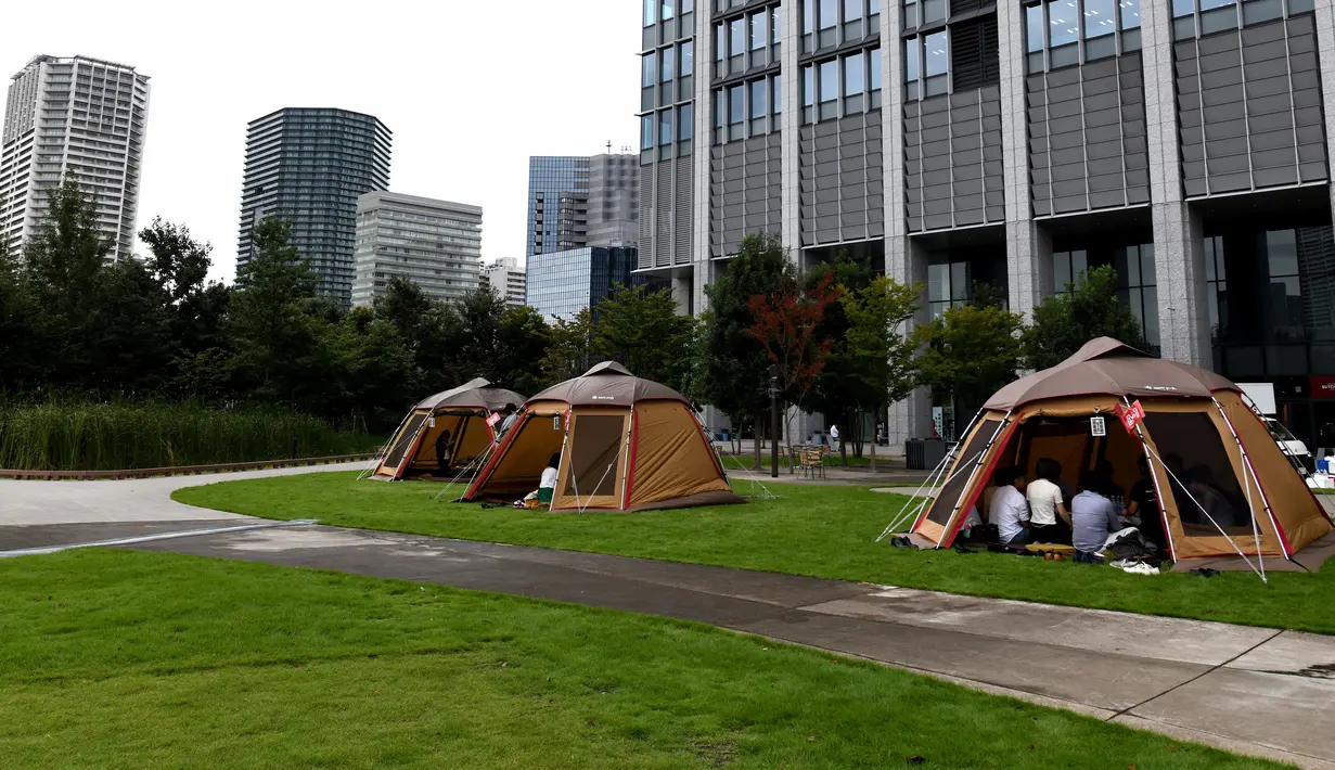 Foto 11 September 2018, karyawan perusahaan bekerja di dalam tenda kemah di halaman luar gedung kantor di Tokyo, Jepang. Tenda-tenda ini adalah kantor outdoor yang disewakan oleh perusahaan Snow Peak Business Solutions. (Toshifumi KITAMURA/AFP)