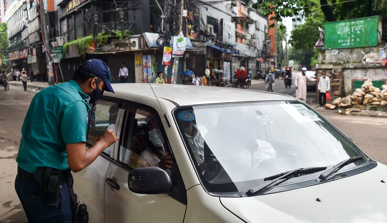 Seorang polisi memeriksa pengendara di sebuah pos pemeriksaan di Dhaka, Bangladesh, Kamis (1/7/2021). Tentara dan polisi diperintahkan untuk mencegah orang-orang keluar rumah, kecuali untuk keadaan darurat atau membeli kebutuhan pokok. (AFP/Munir Uz zaman)