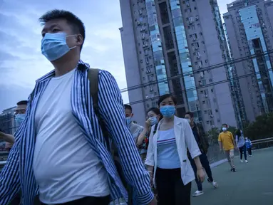 Orang-orang yang memakai masker untuk melindungi diri dari COVID-19 berjalan melintasi jembatan penyeberangan di dekat lingkungan dengan dugaan kasus virus corona di Beijing, Rabu (15/9/2021).. (AP Photo/Mark Schiefelbein)