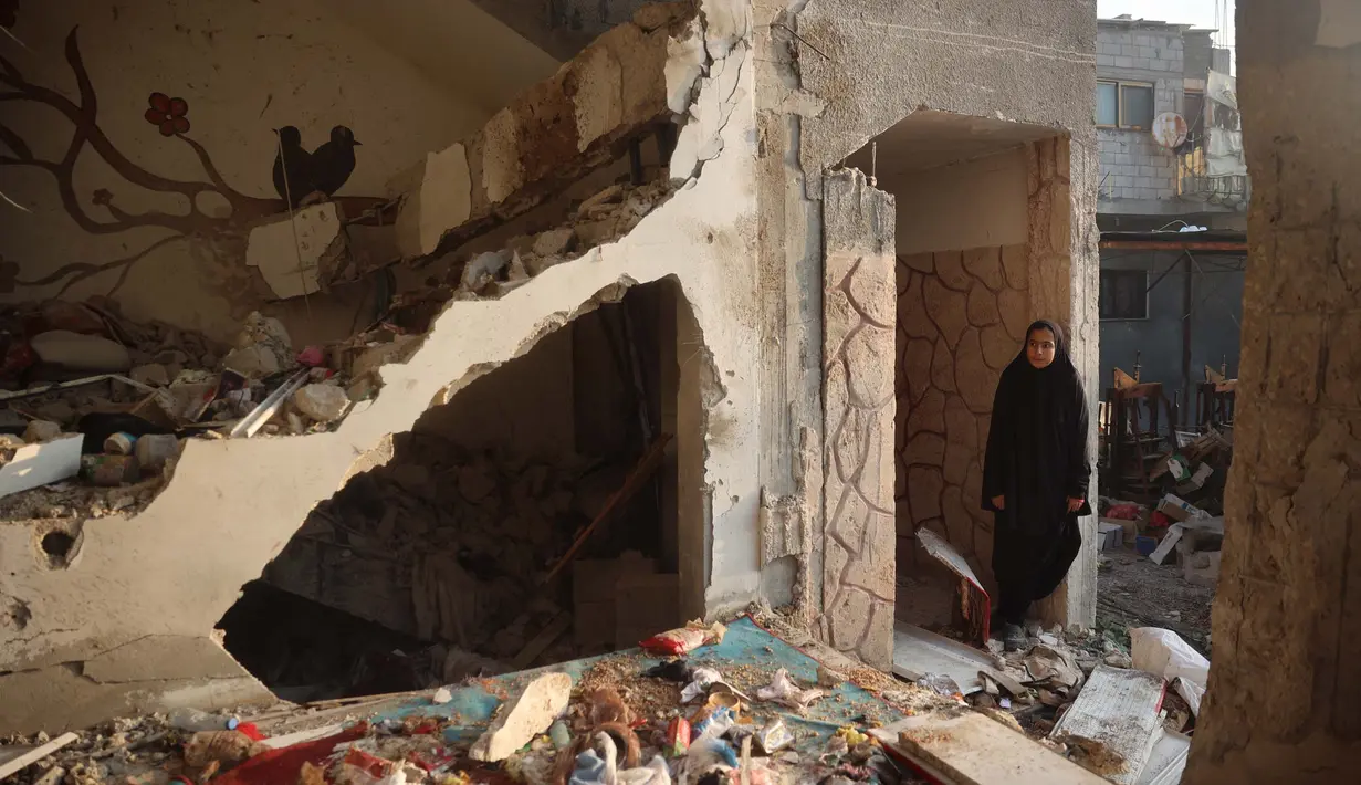 <p>Seorang wanita Palestina berdiri di samping puing-puing di luar gedung yang menjadi sasaran serangan udara Israel pada 12 Desember 2024 di dekat pengungsi Nuseirat di Jalur Gaza tengah. (Eyad BABA/AFP)</p>