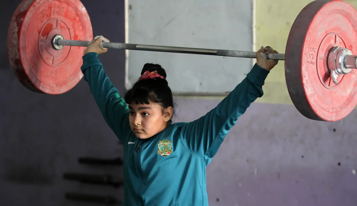 Seorang atlet angkat besi wanita Irak berlatih di sebuah klub di Kota Sadr, sebelah timur Baghdad, Irak (18/1). Jika menang dan membawa medali, hal tersebut dapat membantu meringankan beban keuangan keluarga mereka. (AFP Photo/Ahmad Al-Rubaye)