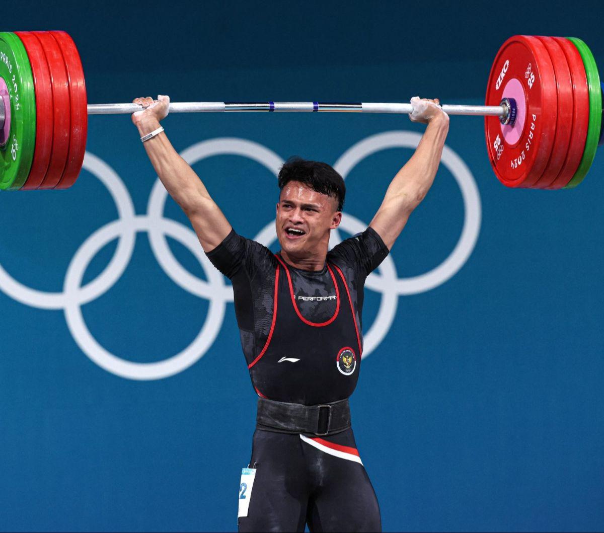 Aksi atlet angkat besi Indonesia, Rizki Juniansyah melakukan angkatan clean and jerk seberat 199 kg saat berdanding dalam nomor 73 kg putra Olimpiade 2024 Paris, Jumat (9/8/2024) dini hari WIB. Berkat perjuangan kerasnya,&nbsp;Rizki berhasil meraih medali