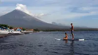 Wisatawan mengayuh kano sambil menyaksikan Gunung Agung yang kembali meletus terlihat dari Karangasem, Bali, Selasa (3/7). Pagi ini, Gunung Agung kembali meletus disertai abu vulkanik setinggi 2.000 meter di atas puncak. (AP Photo/Firdia Lisnawati)