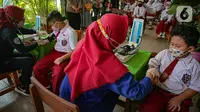 Petugas mengecek kesehatan murid sekolah dasar sebelum menerima vaksinasi COVID-19 di SDN 04 Pagi Cilandak Barat, Jakarta, Selasa (14/12/2021). Pemerintah lewat Kementerian Kesehatan mulai memberikan vaksinasi COVID-19 untuk anak usia 6-11 tahun. (Liputan6.com/Faizal Fanani)