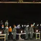 Petugas berdiri di samping peti jenazah korban jatuhnya pesawat Aviastar saat upacara serah terima jenazah di Lanud Sultan Hasanuddin Makassar, Selasa (6/10). 10 jenazah korban Aviastar telah dievakuasi dari pegunungan Bajaja Desa Ulu Salu.(AFP Photo/STR)
