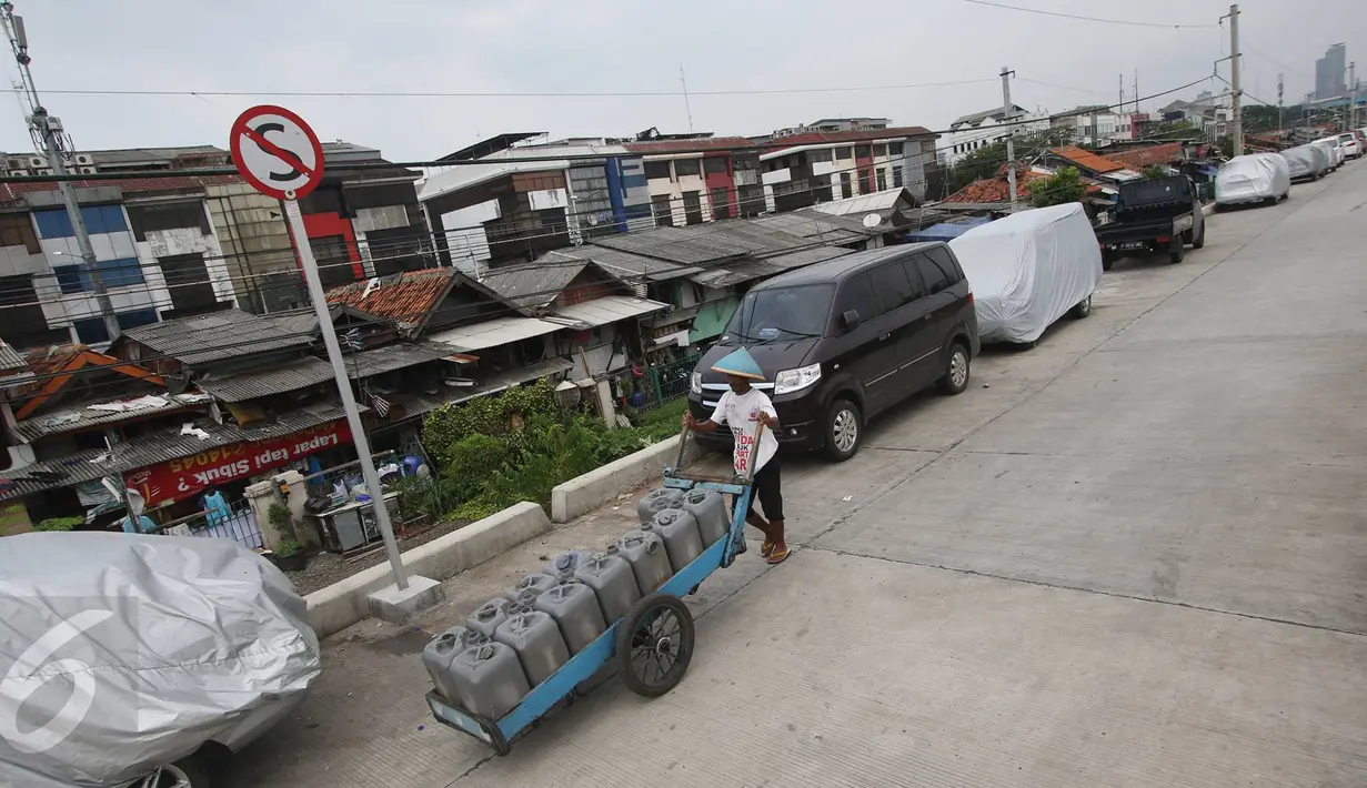Pedagang melintas di jalur inspeksi Kanal Banjir Barat, Jakarta, Senin (6/3). Keterbatasan lahan menyebabkan sejumlah kendaraan parkir di tempat tersebut, meskipun telah terpampang larangan parkir. (Liputan6.com/Immanuel Antonius)