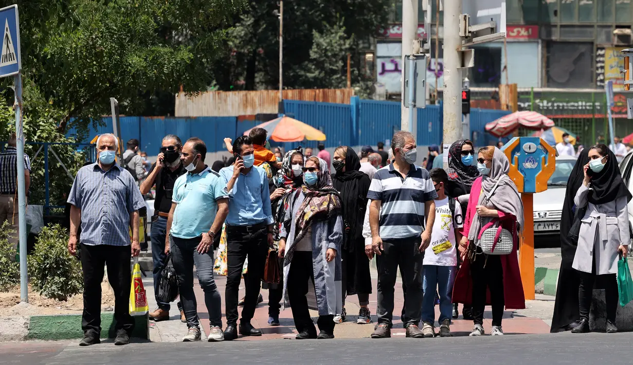 Warga Iran, yang mengenakan masker menunggu di penyeberangan pejalan kaki, di ibu kota Teheran, Sabtu (3/7/2021). Presiden Hassan Rouhani mengaku khawatir Iran akan dilanda gelombang kelima pandemi Covid-19 karena kemunculan virus corona varian Delta. (ATTA KENARE/AFP)