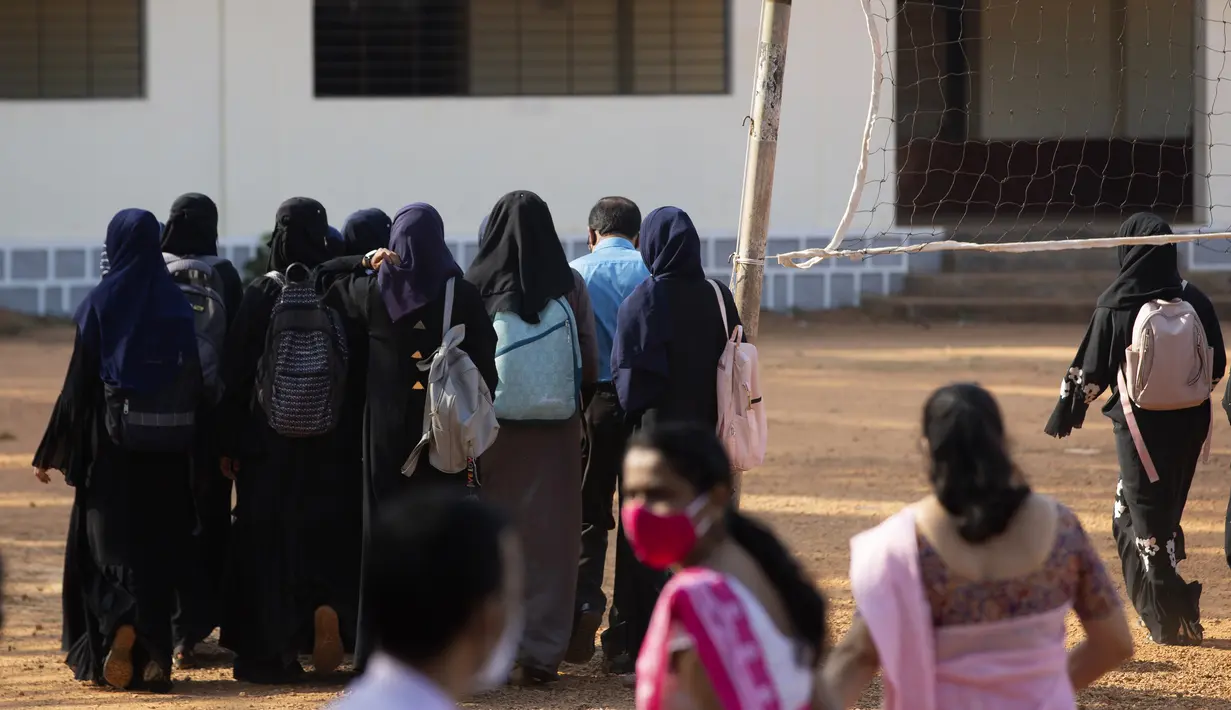 Sejumlah siswi tiba di kampus mereka di Udupi, India (7/2/2022). Dilaporkan ABC News, Selasa (8/2/2022), protes yang terjadi tak membuat staf sekolah tergerak terhadap aksi para murid yang protes di gerbang sekolah yang berlokasi di distrik Udupi. Sekolah itu merupakan milik pemerintah. (AP Photo)