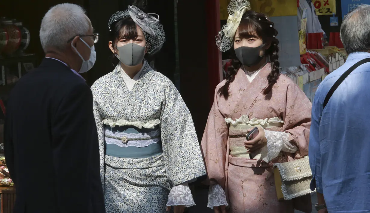 Pengunjung berpakaian kimono yang mengenakan masker untuk melindungi diri dari penyebaran virus corona berjalan-jalan di distrik perbelanjaan Asakusa di Tokyo, Jepang, Rabu (14/10/2020). Tokyo mengonfirmasi lebih dari 170 kasus virus corona baru pada hari Rabu. (AP Photo/Koji Sasahara)