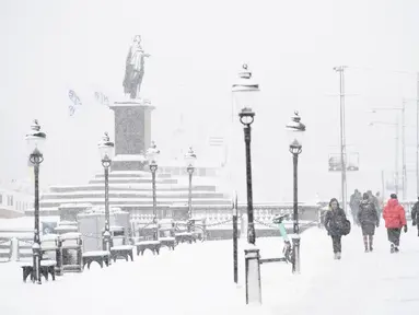 Orang-orang berjalan saat salju turun di Skeppsbron di Stockholm, Swedia (28/1/2021). Badan cuaca nasional Swedia, SMHI, telah mengeluarkan peringatan untuk salju lebat di Stockholm dan Uppsala. (Henrik Montgomery/TT via AP)