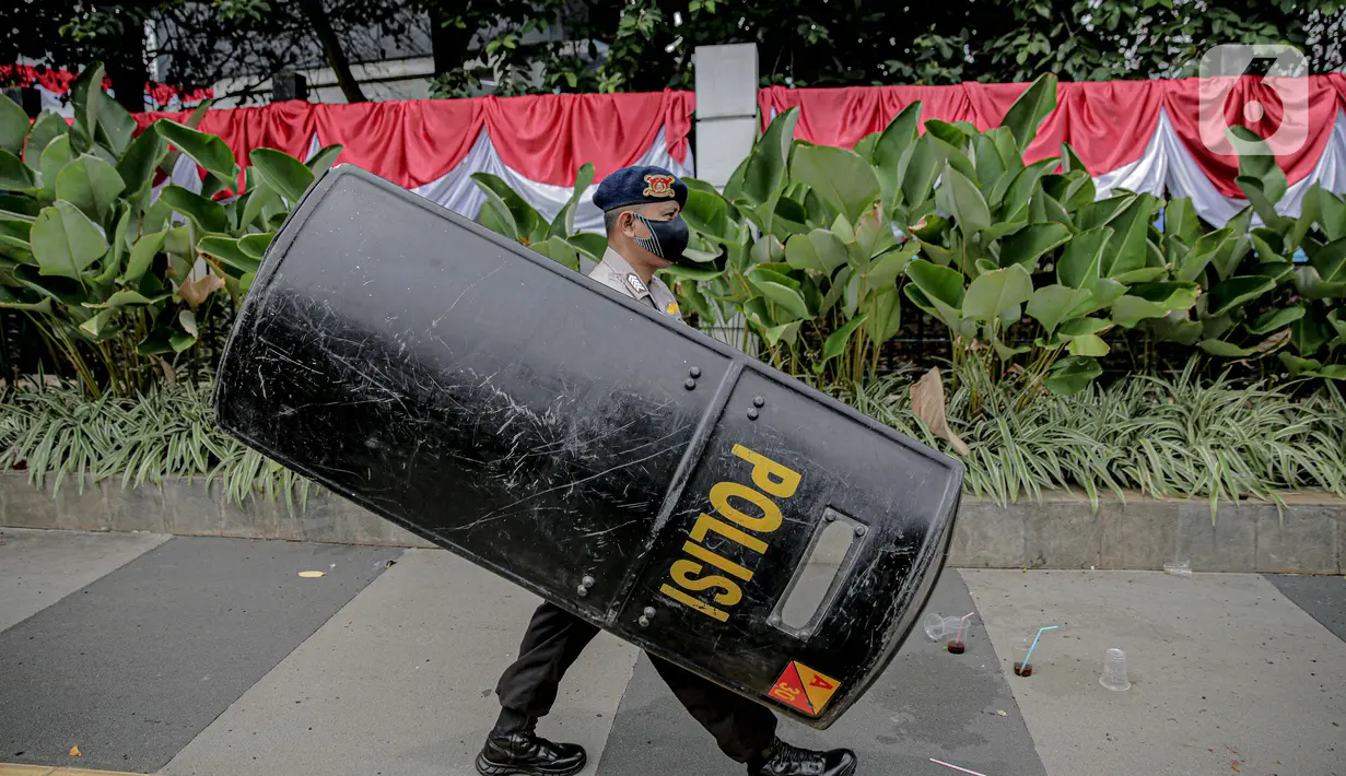 Personel kepolisian dengan membawa tameng bersiap untuk berjaga di sekitar Gedung DPR/MPR RI, Jakarta, Jumat (14/8/2020). Pengamanan ekstra tersebut untuk mengantisipasi rencana unjuk rasa menolak RUU Cipta Kerja yang bertepatan dengan Sidang Tahunan di Gedung DPR. (Liputan6.com/Faizal Fanani)
