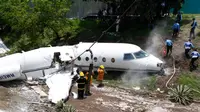 Petugas layanan darurat berada di lokasi kecelakaan pesawat jet pribadi Gulfstream G200 di Bandara Tegucigalpa, Honduras, Selasa (22/5). Badan pesawat itu terbelah menjadi dua bagian setelah tergelincir dari landasan saat mendarat. (AP/Fernando Antonio)
