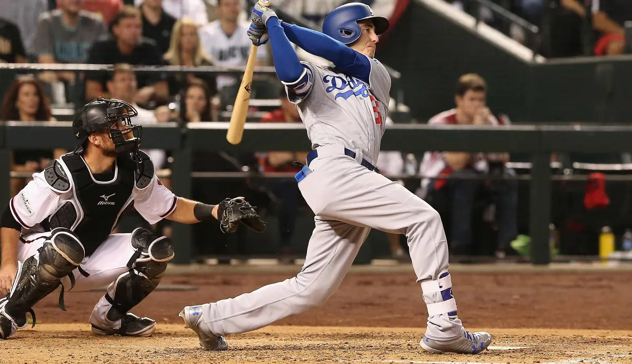 Aksi Cody Bellinger saat memukul bola selama pertandingan kelima dalam game 3 dari Divisi Liga Nasional baseball di Phoenix (9/10). (Christian Petersen / Getty Images / AFP)