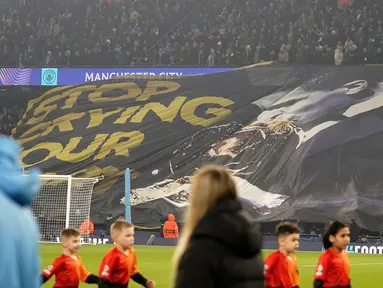 Suporter Manchester City membentangkan spanduk bergambar Rodri yang sedang mencium trofi penghargaan Ballon d'Or dan bertuliskan 'Stop Crying Your Heart Out' dalam laga leg 1 babak playoff Liga Champions 2024/2025 melawan Real Madrid di Etihad Stadium, Manchester, Inggris, Rabu (12/02/2025) WIB. (AP Photo/Dave Thompson)