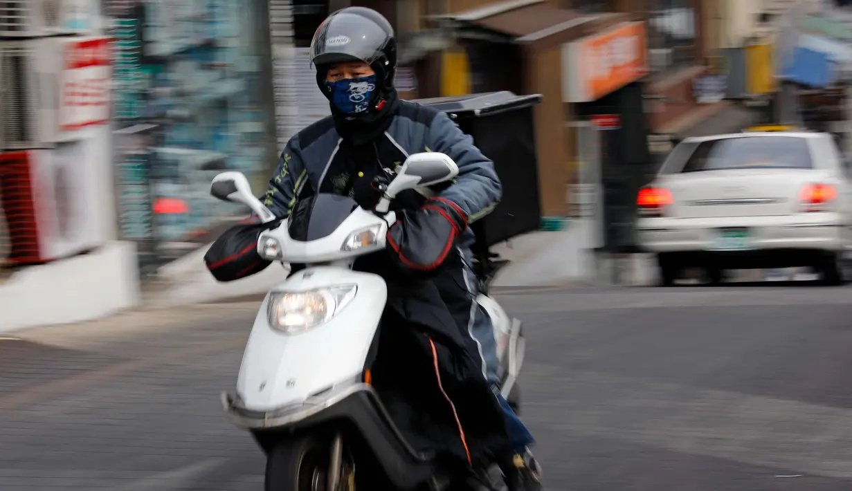 Seorang pria mengendarai skuter di sebuah jalan di Seoul, Korea Selatan, (19/2). (AFP Photo/David Gannon)