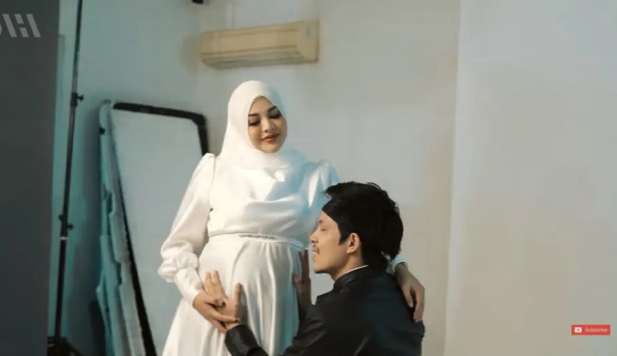 Pada konsep kedua, pasangan ini memilih mengenakan nuansa hitam putih. Aurel mengenakan dress satin berwarna putih dengan detail puff sleeve. Sementara Atta memilih mengenakan jaket kulit yang dipadukan dengan kemeja putih. (YouTube/AH)