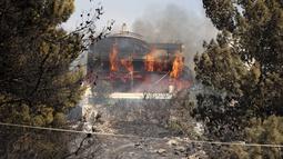 Api membakar sebuah rumah saat kebakaran hutan di pinggiran Voula, di selatan Athena, Yunani, Sabtu, 4 Juni 2022. Kebakaran hutan berkobar di luar kendali di pinggiran Athena, hingga merusak rumah-rumah dan mobil di permukiman warga. (AP Photo/Yorgos Karahalis)