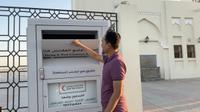 WNI di Qatar, Bakhtiar Sutanto, menunjukkan kotak amal yang disediakan pemerintah setempat untuk mempermudah warganya beramal. (Bola.com/Ade Yusuf Satria)