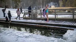 Seorang wanita mengeringkan dengan handuk setelah mandi di air es danau dekat Vilnius, Lithuania, Minggu (13/2/2022). Suhu udara 0 derajat Celcius (32 derajat Fahrenheit). (AP Photo/Mindaugas Kulbis)