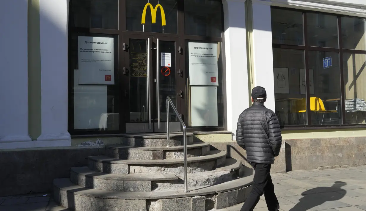 Seorang pria berjalan melewati restoran McDonald's yang tertutup untuk pengunjung di St. Petersburg, Rusia, Selasa (15/3/2022). Penutupan ini dilakukan pihak McDonald's sebagai sikap atas invasi Rusia ke Ukraina yang berlangsung dari 24 Februari 2022 lalu. (AP Photo)