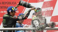 Juara MotoGP Argentina, Cal Crutchlow dari tim LCR Honda menyemprotkan sampanye pada pembalap Yamaha Tech 3, Johann Zarco di atas podium Sirkuit Termas de Rio Hondo, Minggu (8/4). Crutchlow berhasil menjadi juara MotoGP Argentina. (AP/Natacha Pisarenko)