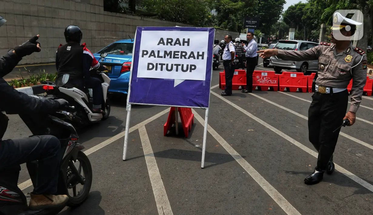 Polisi mengarahkan pengendara sepeda motor yang melintas di sekitar Gedung DPR RI, Jakarta, Kamis (17/10/2019). Polisi kembali menutup sejumlah ruas jalan menuju kawasan Gedung DPR RI guna menjaga kondusifitas jelang pelantikan Presiden dan Wakil Presiden terpilih. (Liputan6.com/JohanTallo)