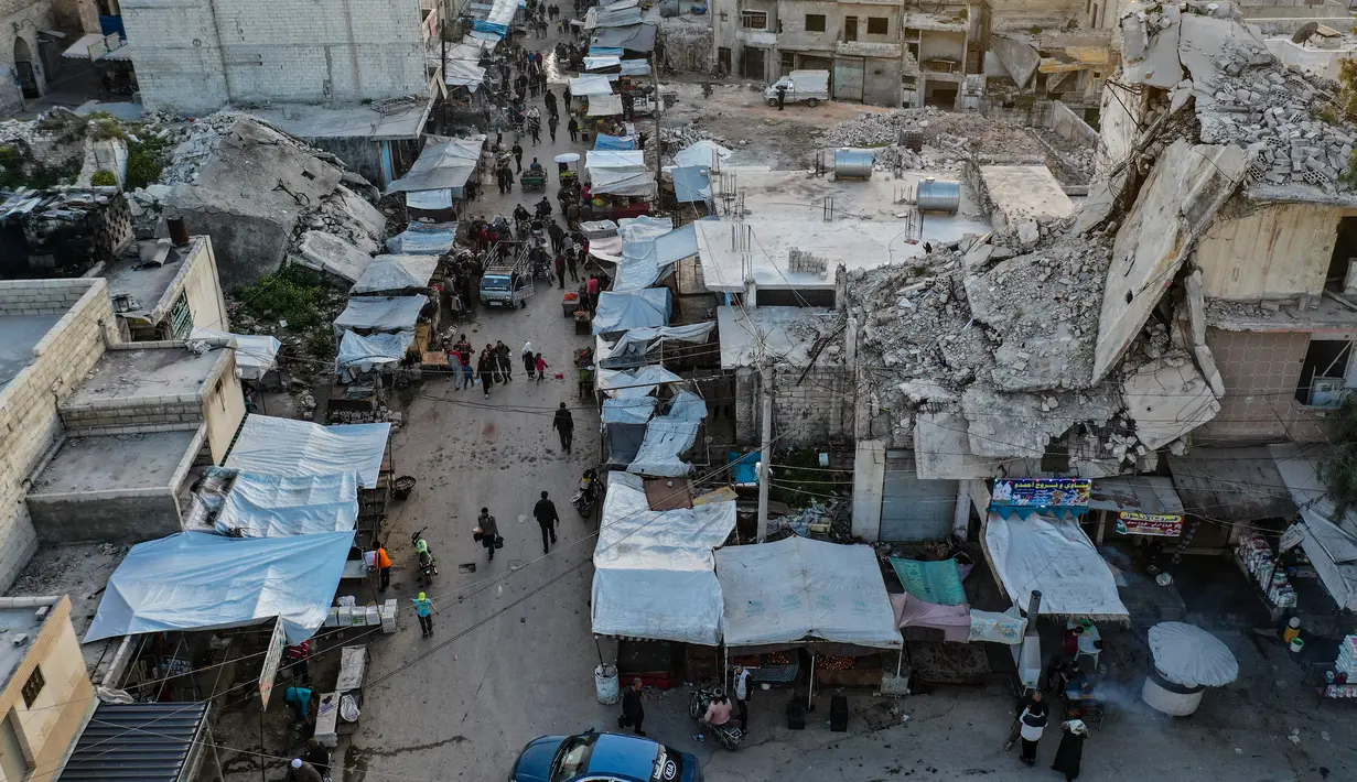Pemandangan udara saat warga Suriah membeli produk makanan di pasar menjelang buka puasa pada hari kedua Ramadhan, di kota Ariha yang dilanda perang, di provinsi Idlib, Kamis (15/4/2021). Mereka menjalankan Ramadhan di antara lautan reruntuhan bekas konflik gencatan senjata. (Omar HAJ KADOUR/AFP)
