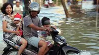 Seorang pengendara motor bersama keluarga melewati genangan banjir, di Kabupaten Sampang, Madura, Jatim.(Antara)