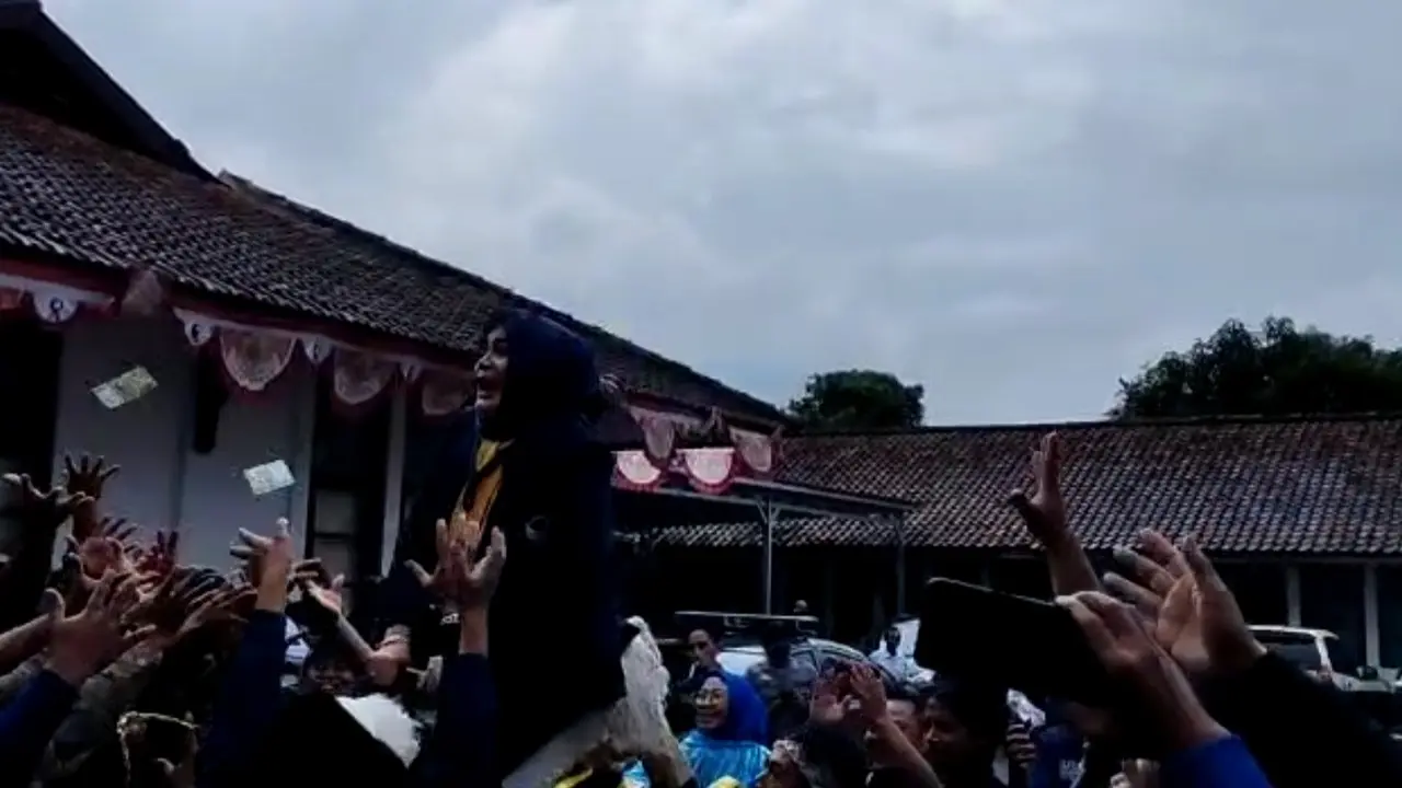 Ketua DPD Nasdem Kabupaten Garut, sekaligus istri Bupati Garut Diah Kurniasari, melakukan saweran uang di halaman kantor KPUD Garut, selepas pendaftaran bakal calon anggota legislatif (caleg) Pemilu 2024, Kamis (11/5/2023). (Liputan6.com/Jayadi Supriadin)