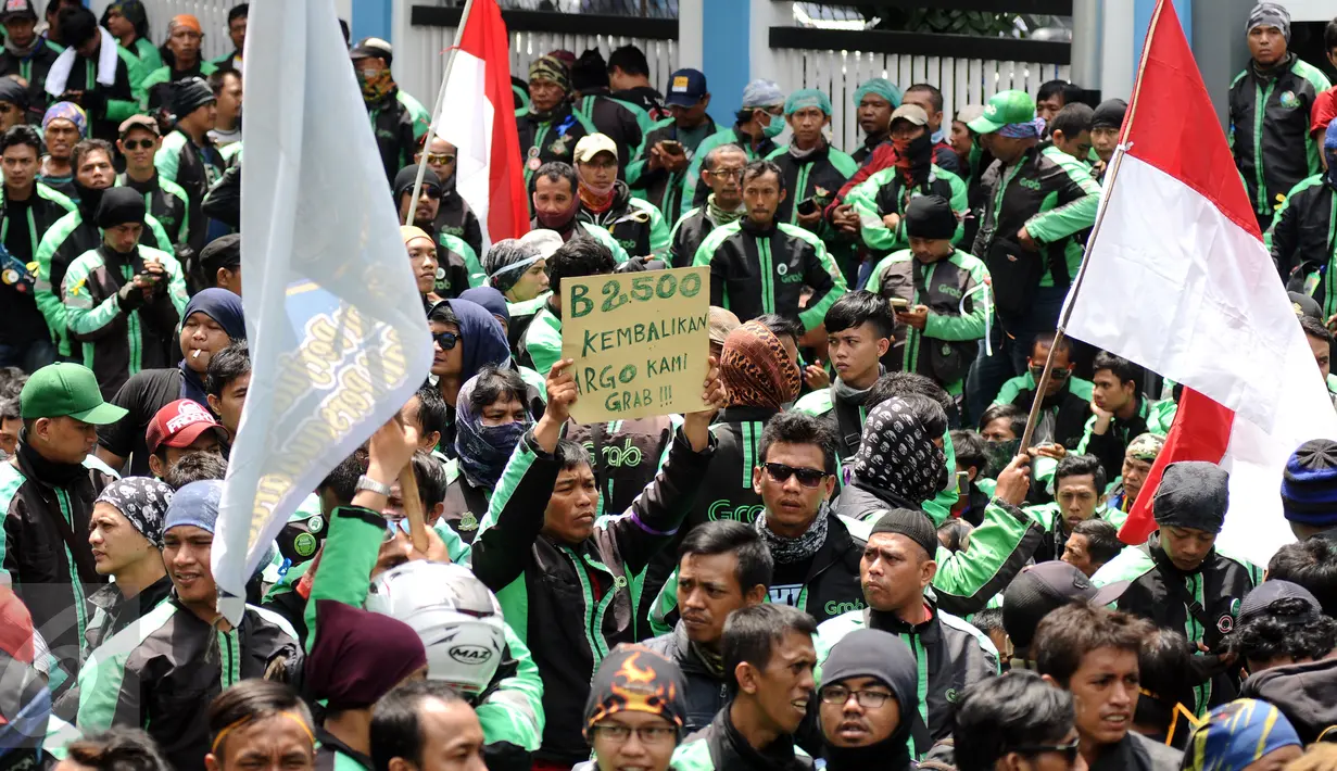 Pengemudi ojek on-line GrabBike mengangkat tulisan tuntutan saat unjuk rasa di belakang kantor Grab di kawasan Kuningan, Jakarta, Kamis (5/1). Mereka menuntut pihak perusahaan menaikkan tarif argo per kilometernya. (Liputan6.com/Helmi Fithriansyah)