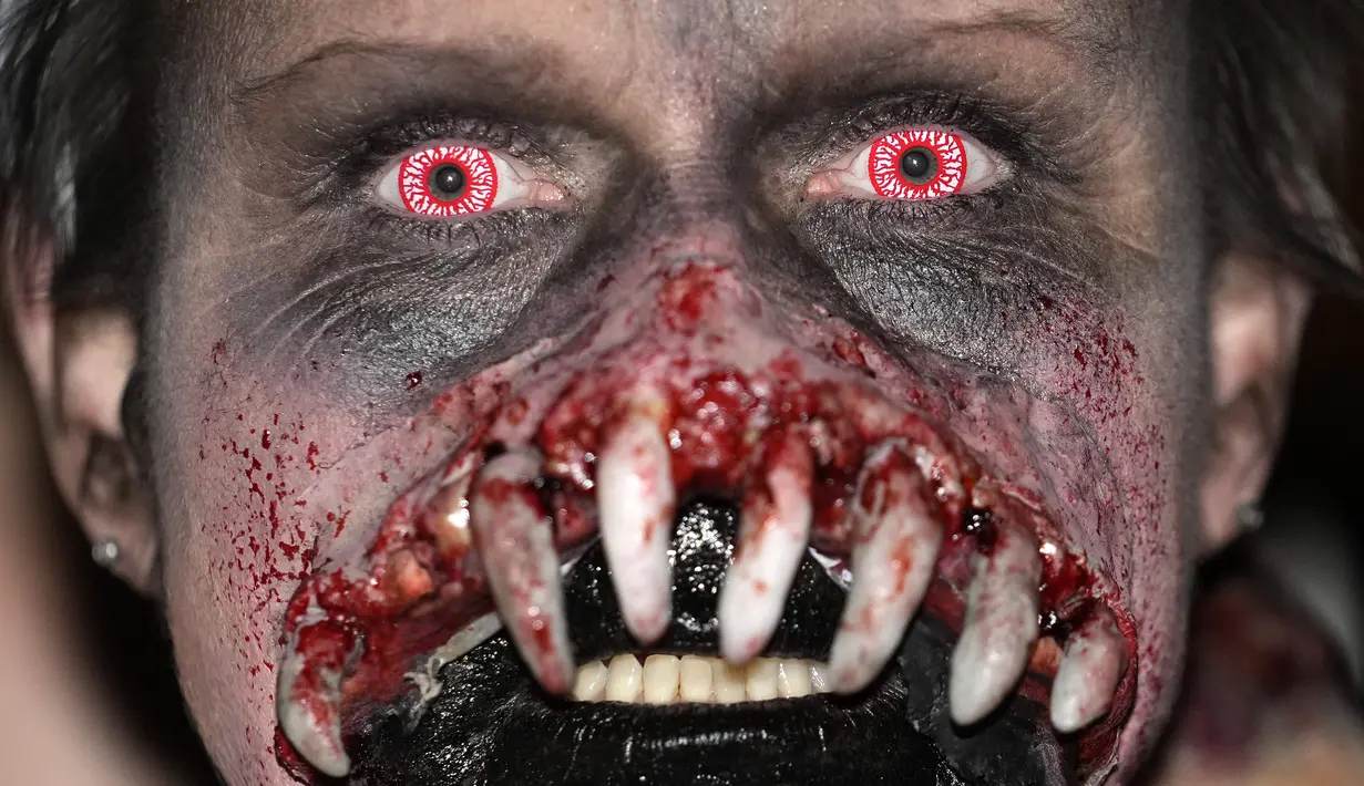 Seseorang yang mengenakan kostum menakutkan berpartisipasi dalam Zombie Walk dan Parade Halloween tahunan di Essen, Jerman, Minggu (31/10/2021). Setiap 31 Oktober sebagian masyarakat dunia ikut memeriahkan perayaan Halloween. (AP Photo/Martin Meissner)