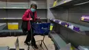 Warga mengenakan masker berjalan melewati rak kertas tisu yang kosong di sebuah supermarket di Hong Kong, Kamis (6/2/2020). Di tengah kelangkaan masker wajah untuk melindungi terhadap wabah virus corona, tisu toilet tiba-tiba juga menjadi salah satu barang yang langka di Hong Kong. (AP/Vincent Yu)