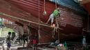 Para pekerja saat memperbaiki sebuah kapal di galangan kapal di tepi Sungai Yangon, yang terletak di pinggiran Yangon, Myanmar (30/7/2019). (AFP Phot/Sai Aung Main)