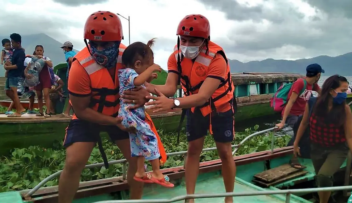 Anggota Penjaga Pantai Filipina membawa seorang anak saat mereka dievakuasi ke tempat yang lebih aman menyusul peringatan menghadapi topan Goni di provinsi Camarines Sur, Filipina (31/10/2020). (Philippine Coast Guard via AP)