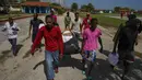 Imigran Haiti membantu anggota Palang Merah mendistribusikan handuk dan perlengkapan mandi ke seluruh kelompok mereka di sebuah perkemahan yang digunakan untuk menampung sekelompok besar migran Haiti di Sierra Morena di provinsi Villa Clara Kuba, Kamis (26/5/2022). (AP Photo/Ramon Espinosa)