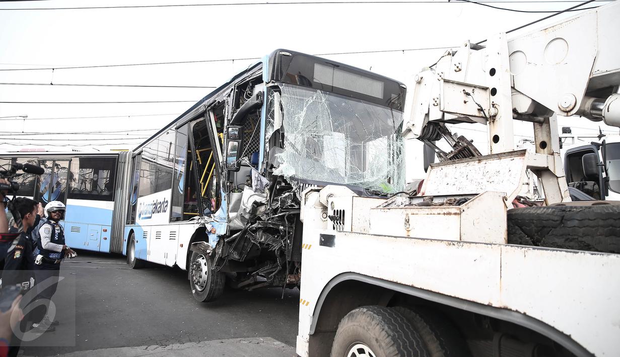 Badan bus Transjakarta dipindahkan dari lokasi kecelakaan di perlintasan Jalan Mangga Dua, Jakarta, Kamis (19/5). Sebelumnya, sebuah kecelakaan terjadi melibatkan bus transjakarta, mobil Avanza dan Kereta Senja Utama Solo. (Liputan6.com/Faizal Fanani)