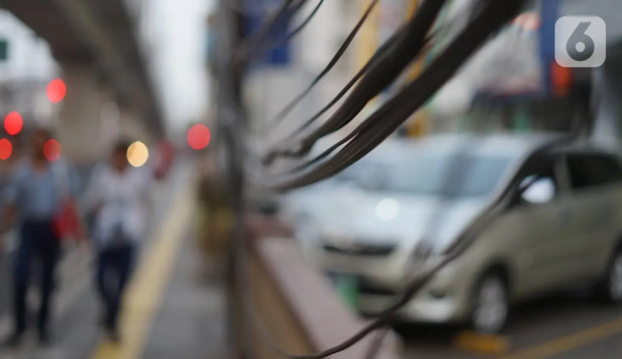 Instalasi kabel menjuntai di Jalan Panglima Polim, Kebayoran Baru, Jakarta, Kamis (31/10/2019). Buruknya pemasangan instalasi kabel di Ibukota menyebabkan banyak kabel yang menjuntai hingga mengganggu ketertiban umum. (Liputan6.com/Immanuel Antonius)