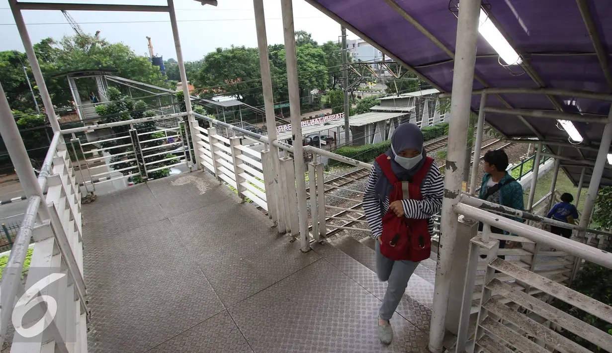 Warga melintasi Jembatan Penyeberangan Orang di kawasan Tanjung Barat, Jakarta, Jumat (11/11).Buruknya desain menyebabkan JPO tersebut tidak tersambung, sehingga warga harus membeli tiket kereta jika ingin menyeberang. (Liputan6.com/Immanuel Antonius)