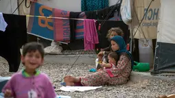 Seorang bocah menjaga adiknya di sebuah kamp di Hammam al-Alil, Irak, Rabu (3/5). Pengungsi di kamp ini adalah warga Irak yang menyelamatkan diri dari ISIS di Mosul Barat. (AFP PHOTO / FADEL SENNA)