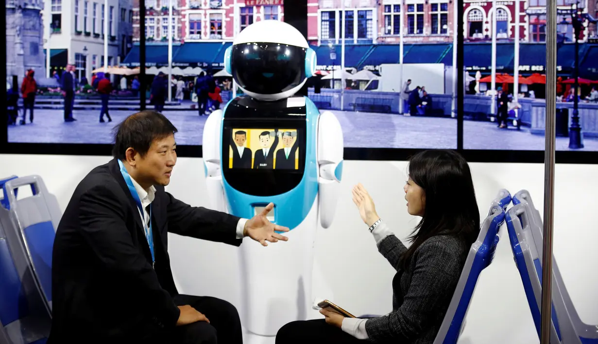 Pengunjung berbincang di depan robot simulasi angkutan umum di Konferensi Robot Dunia WRC 2016 di Beijing, Tiongkok (21/10). Pameran robot kelas dunia ini berlangsung dari 21 - 25 Oktober. (Reuters/Thomas Peter)