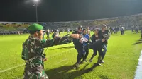 Salah seorang pendukung Arema FC digotong rekannya saat kericuhan duel Arema FC Vs Persib Bandung (Rana Adwa/Liputan6.com)