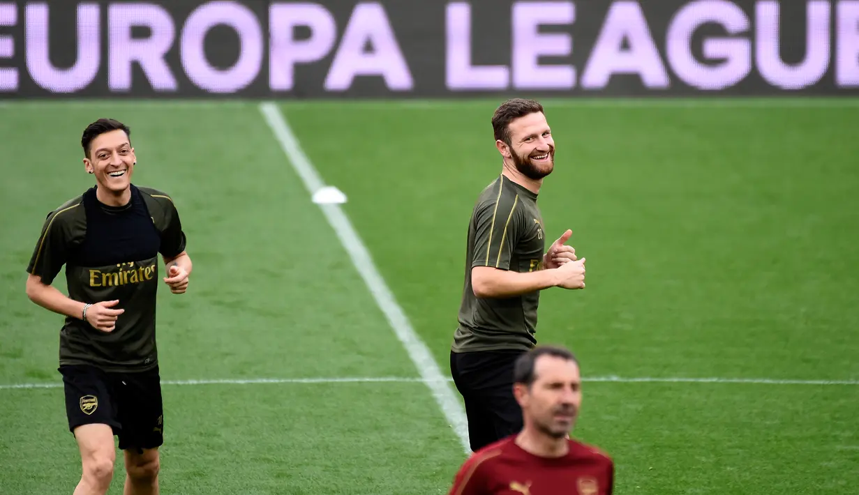 Gelandang Arsenal asal Jerman, Mesut Ozil (kanan) dan bek Shkodran Mustafi melakukan pemanasan selama sesi latihan tim di stadion Mestalla di Valencia, Spanyol (8/5/2019). Arsenal akan bertanding melawan Valencia pada leg kedua babak semifinal Liga Europa di Mestalla. (AFP Photo/Jose Jordan)