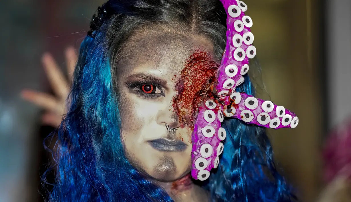 Seorang perempuan yang mengenakan kostum menakutkan berpartisipasi dalam Zombie Walk dan Parade Halloween tahunan di Essen, Jerman, Minggu (31/10/2021). Setiap 31 Oktober sebagian masyarakat dunia ikut memeriahkan perayaan Halloween. (AP Photo/Martin Meissner)