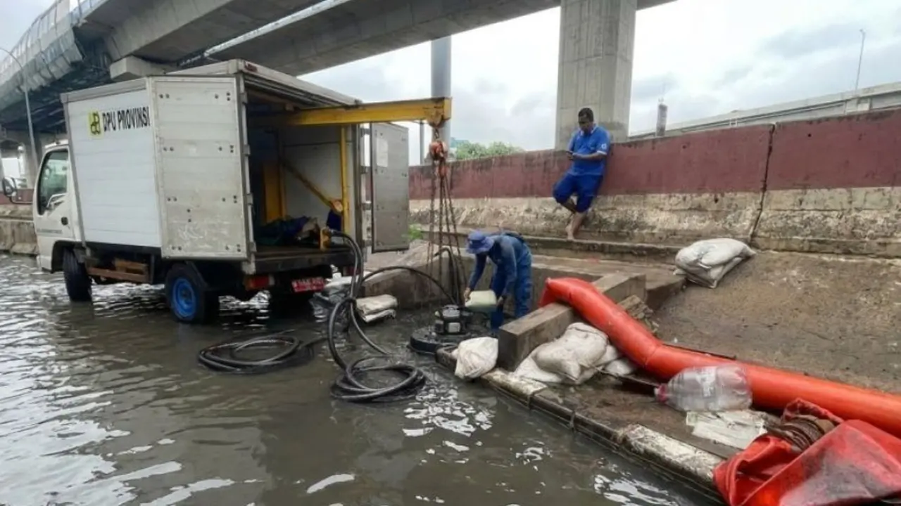 Petugas Suku Dinas Sumber Daya Air Jakarta Utara (SDA Jakut) menangani banjir rob yang terjadi di Jalan RE Martadinata, Jakut, Jumat (2/1/2026).