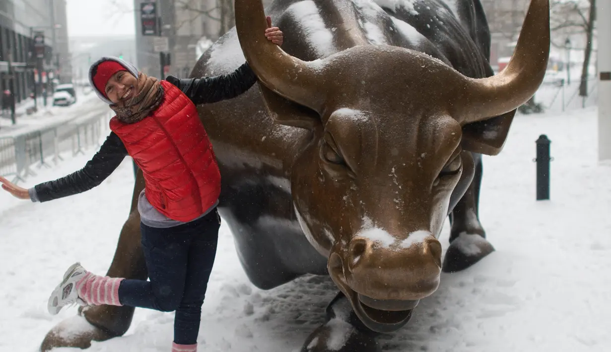 Seorang turis berpose di samping banteng di Broadway, New York (14/3). Badai salju menerjang kawasan Amerika Serikat timur laut, dari West Virginia hingga Maine, menyebabkan hujan salju lebat di sejumlah tempat. (AFP Photo/Don Emmert)