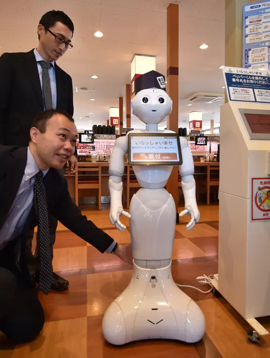 Karyawan dari pengembang robot humanoid Pepper mendemonstrasikan robotnya saat press preview di Saitama, Jepang (2/2). Robot tersebut dapat melayani pelanggan dan membuka pintu masuk ke meja resepsionis. (AFP/Kazuhiro Nogi)